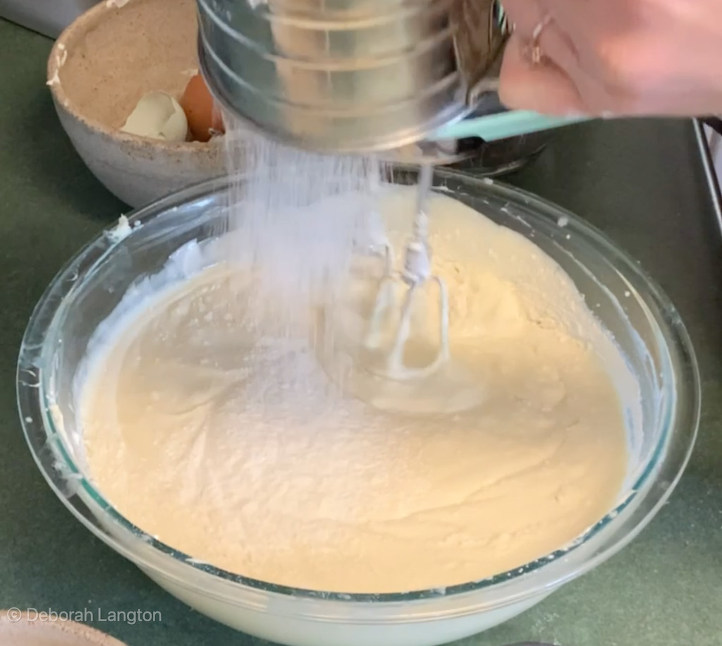 Sifting flour while mixing classic cheesecake recipe