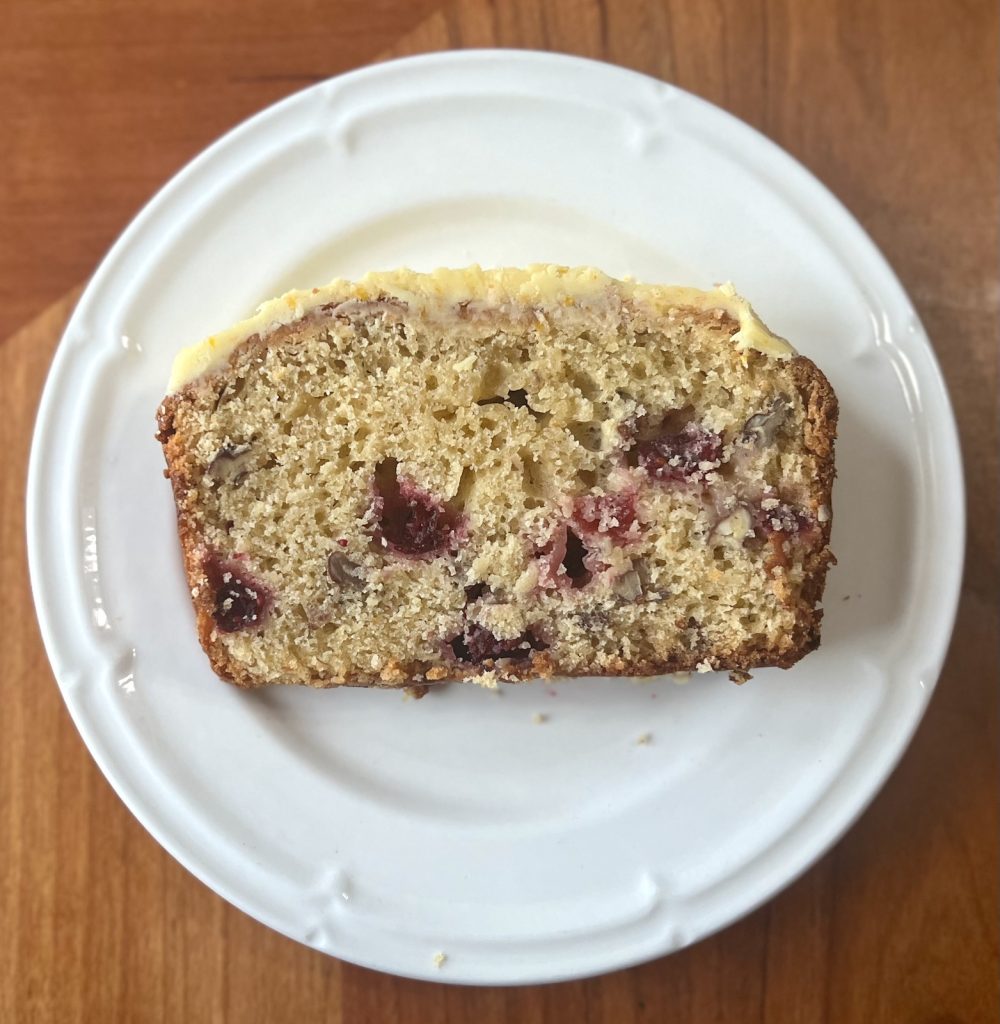 Single slice of cranberry orange sourdough loaf showing cranberries and pecans in the crumb.