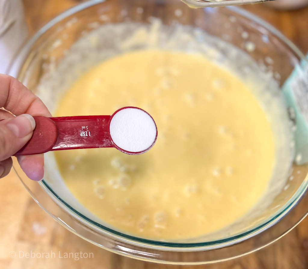 baking soda in a measuring spoon over batter bowl