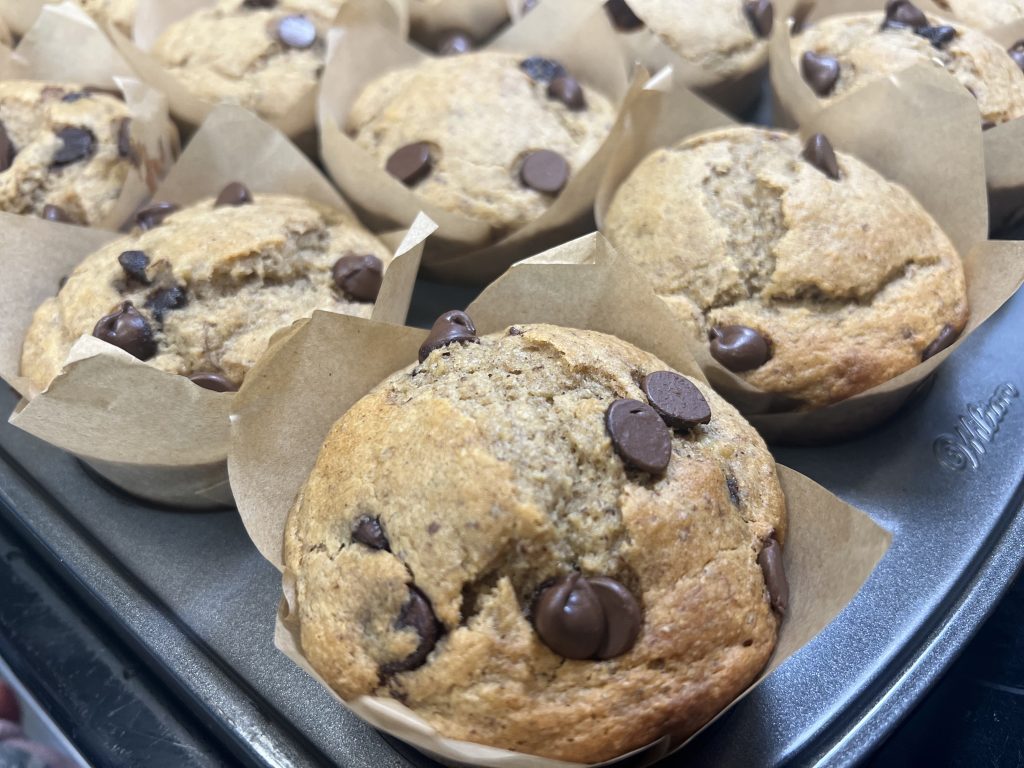 Fresh-milled banana chocolate chip muffins cooling in brown parchment liners