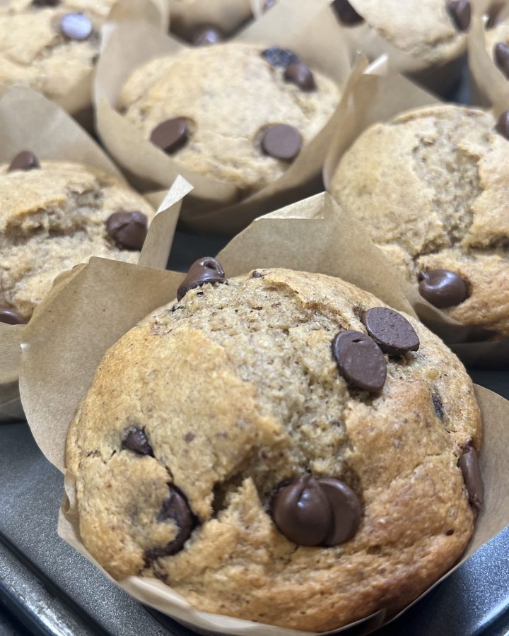 Fresh-milled banana chocolate chip muffins cooling in brown parchment liners
