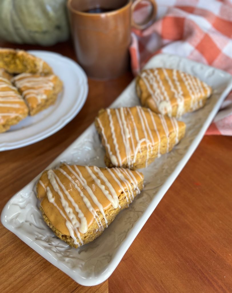 Glazed pumpkin sourdough discard scones arranged on a white rectangular serving platter