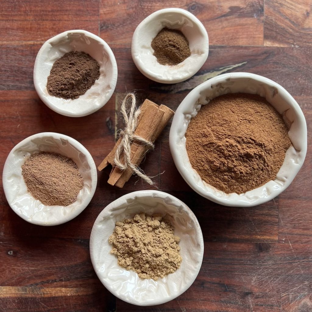 Ground cinnamon, ginger, nutmeg, allspice, and cloves in small bowls for homemade pumpkin pie spice