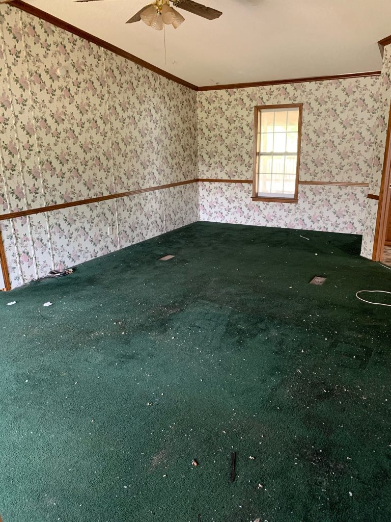 Bedroom before renovation with green carpet and floral wallpaper
