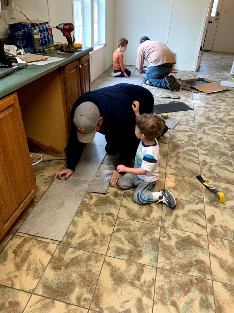 Trey, brother and the children installing flooring during the family home renovation