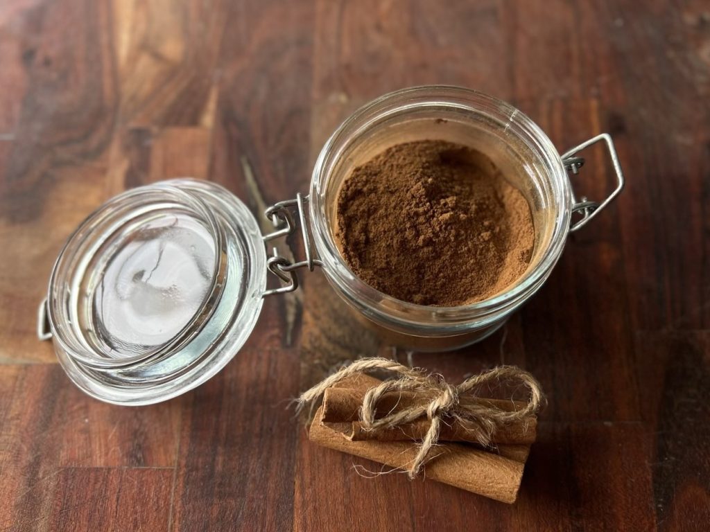 Homemade pumpkin pie spice in a glass latch jar with cinnamon sticks