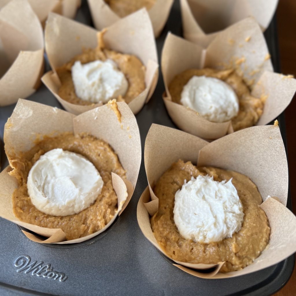 Sweetened cream cheese spooned onto pumpkin muffin batter before baking