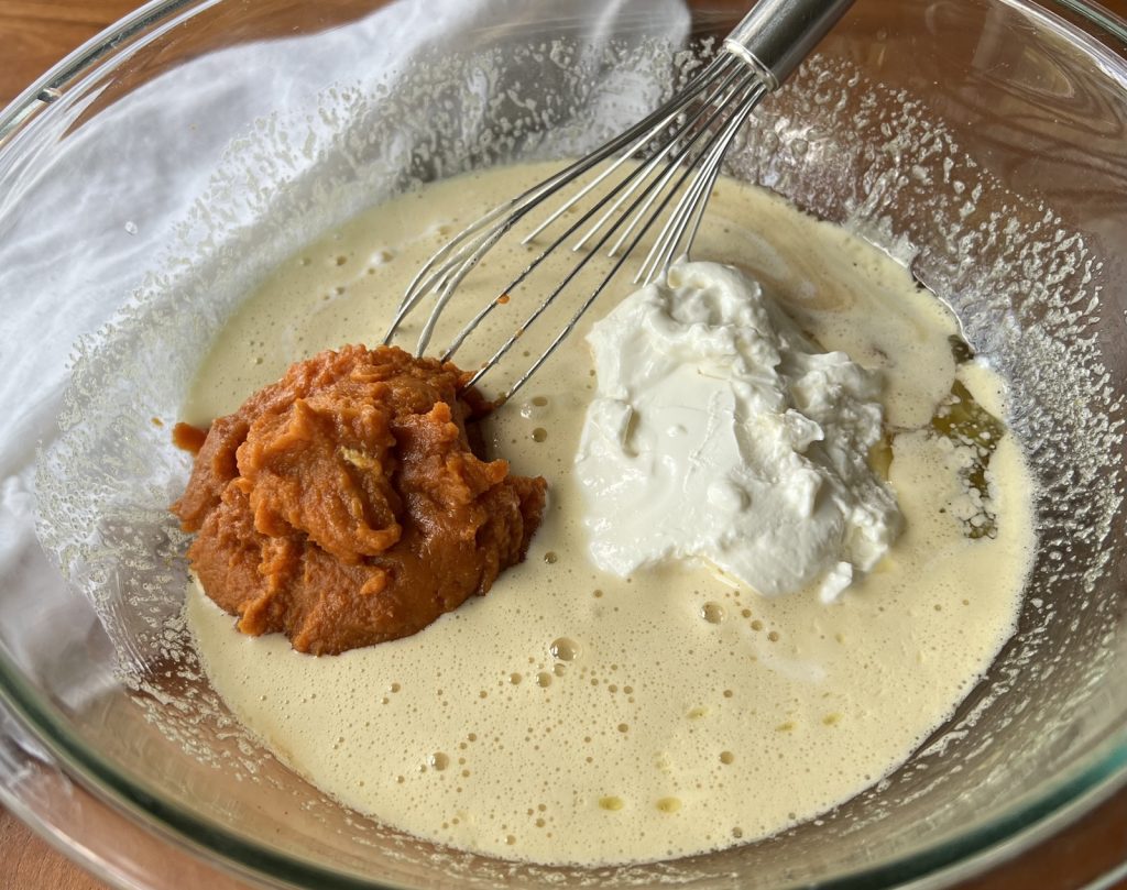 Pumpkin, buttermilk, yogurt, eggs, butter, oil, and vanilla whisked together in a glass bowl
