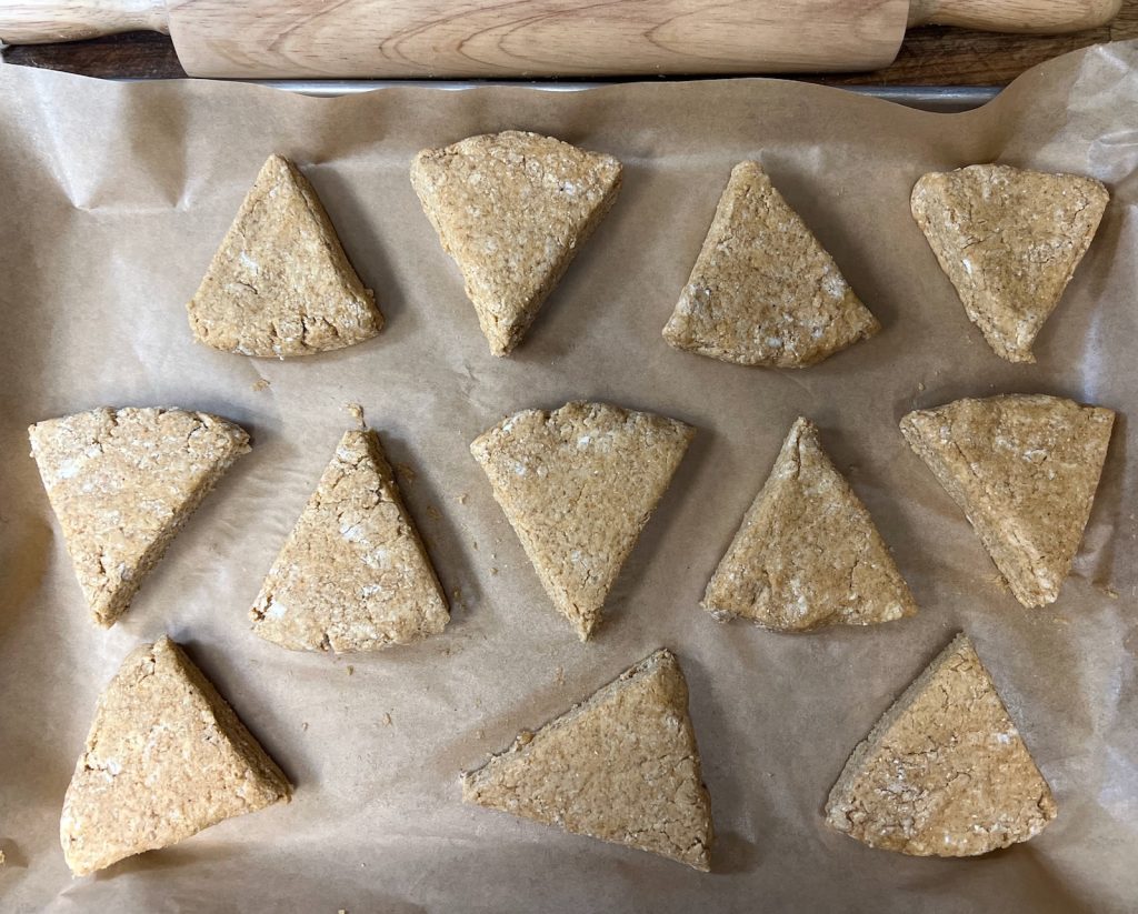 Twelve unbaked pumpkin sourdough discard scones arranged on a parchment-lined baking sheet.