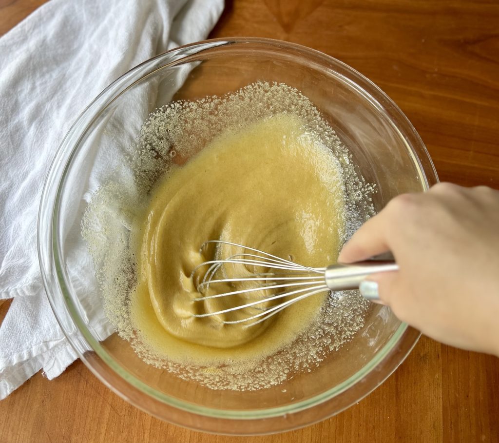 Eggs and cane sugar being whisked together for fresh-milled pumpkin muffins.