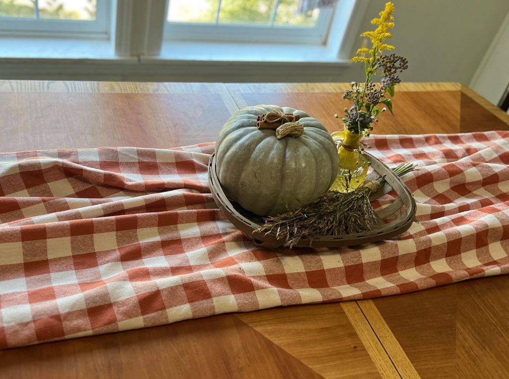 A low fall centerpiece on a wooden family dining table.