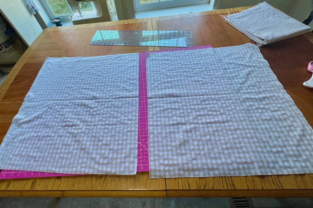 Two beige gingham panels laid flat on a cutting mat before sewing.